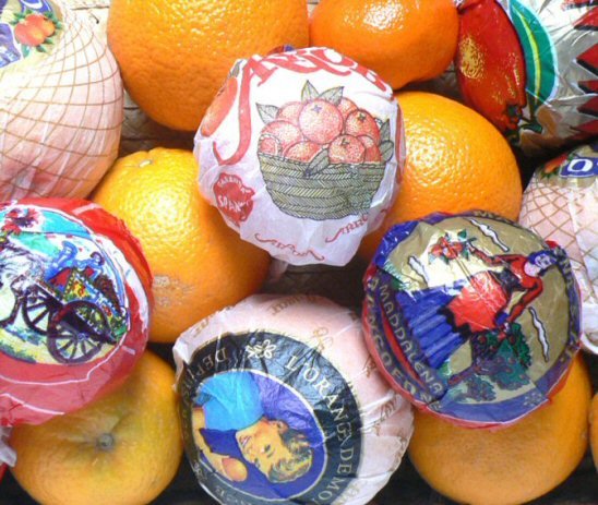 Papiers de fruits illustrés enveloppant des oranges et clémentines.